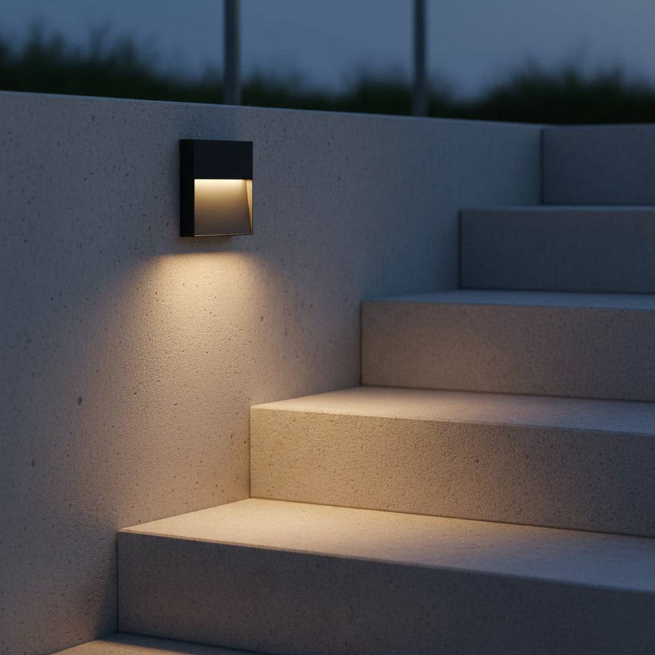 black LED stair light outdoor mounted on a concrete wall next to outdoor stairs 