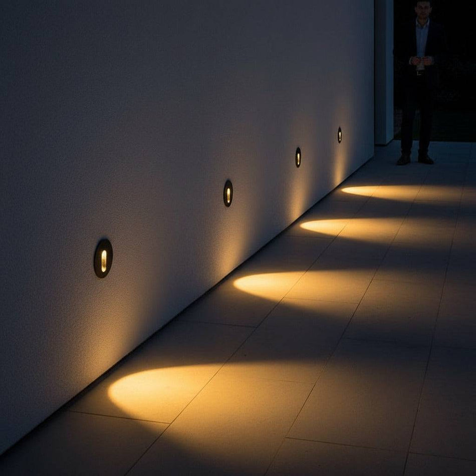 black outdoor stair step light mounted in a row along an outside wall shining light downwards