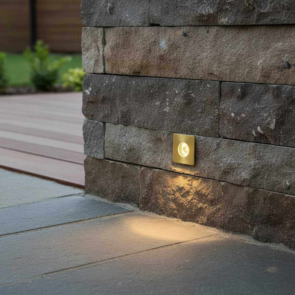 brass decking ground light recessed into a stone wall outside