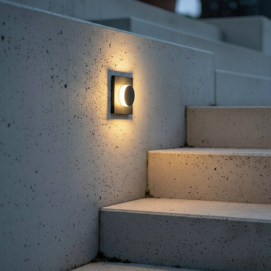 black flush mounted sconce light mounted on a concrete wall next to outdoor steps 