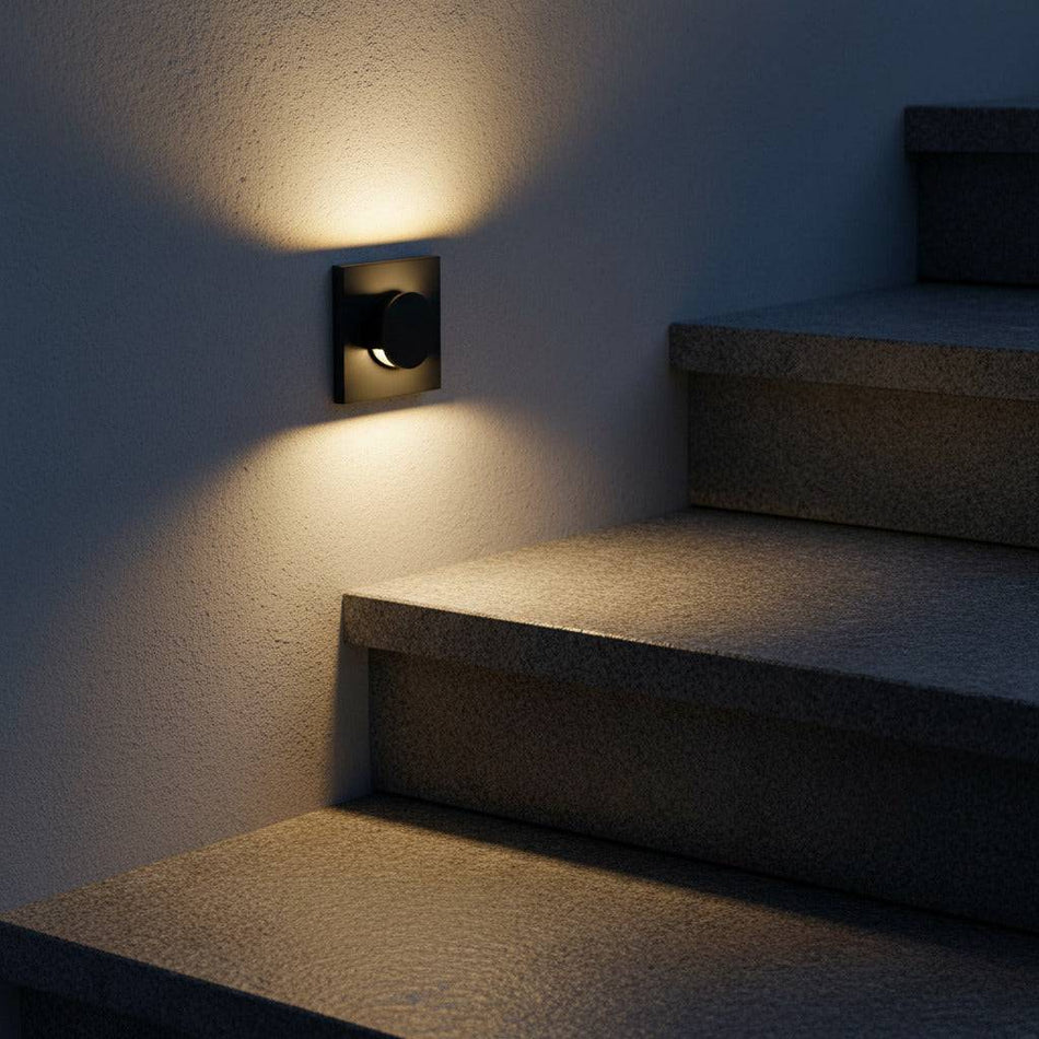 black recessed outdoor wall light mounted on the wall next to some outdoor concrete steps 