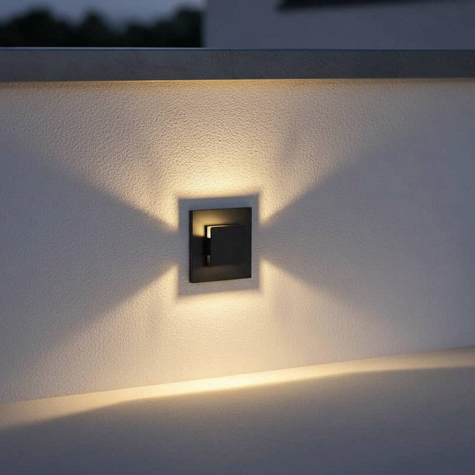 black recessed outdoor wall light mounted at low level on a white outdoor wall 