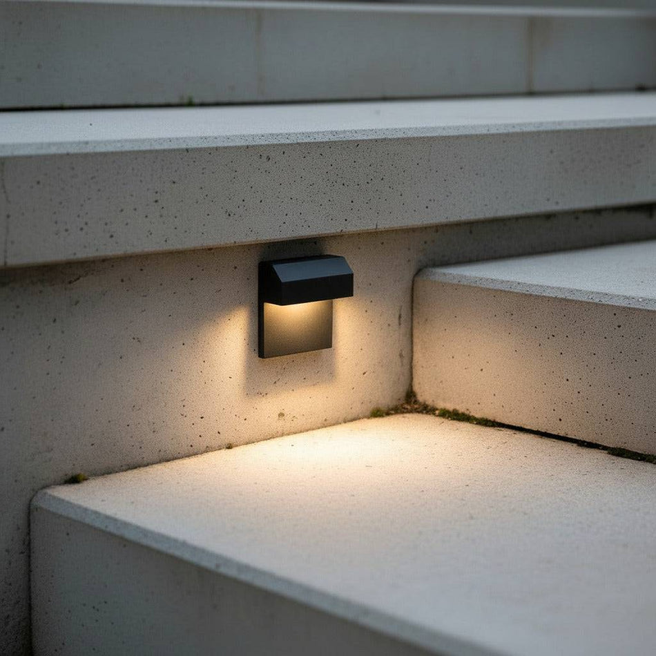 black light for outdoor stairs mounted on a concrete wall next to a step 