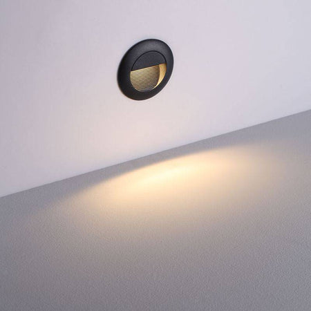 black outdoor stair light mounted at low level on a white wall 