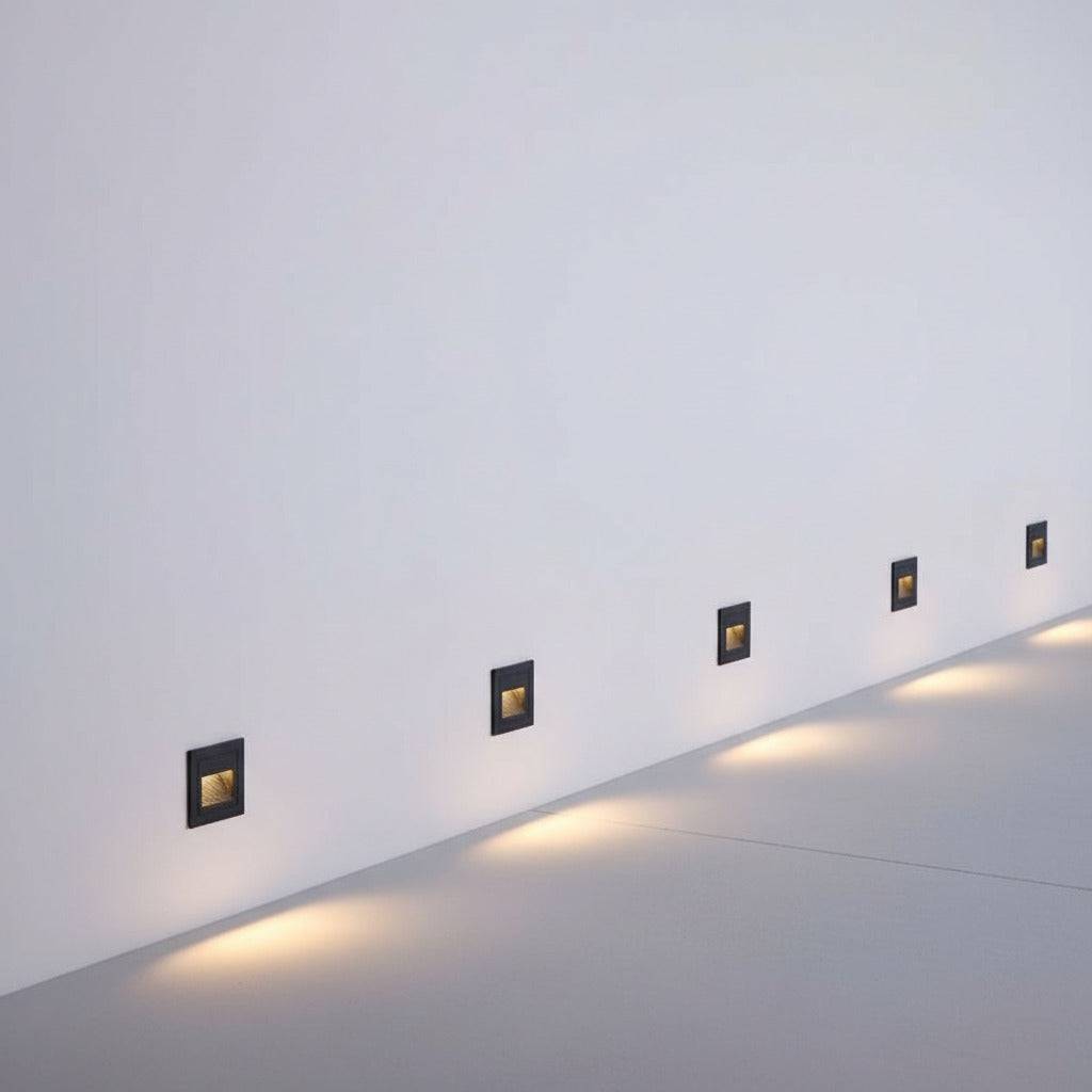 black stair step lighting mounted in a row on a white wall at low level 