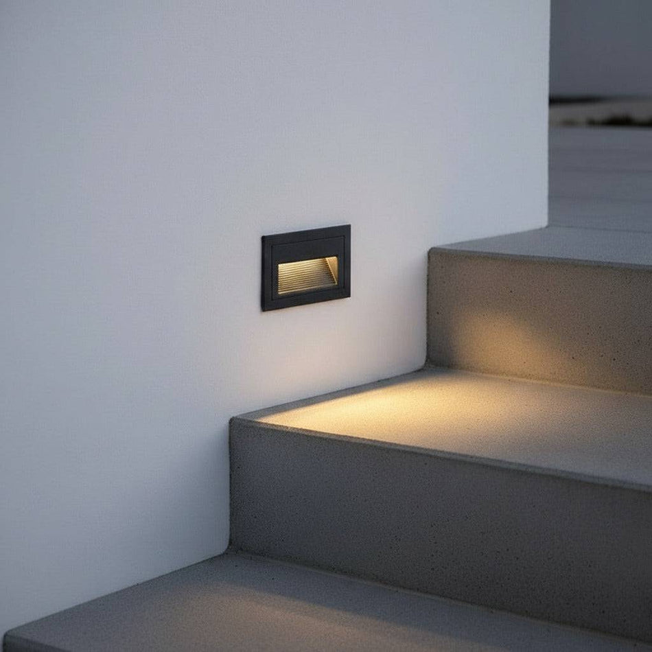 black low level external wall light mounted in the wall alongside some outdoor steps 