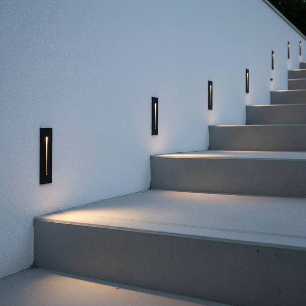 black flush mounted exterior wall light mounted on the wall outside next to some concrete steps 