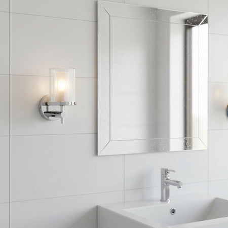 polished chrome bathroom wall light installed next to a bathroom mirror 