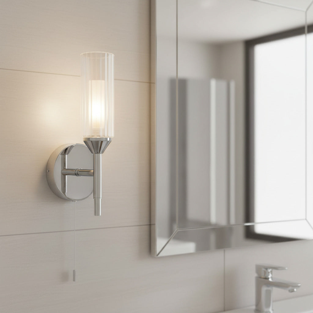 chrome bathrom wall light with pull cord mounted next to a bathroom mirror 