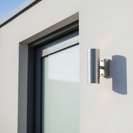 stainless steel external up down light mounted next to the door of a modern house
