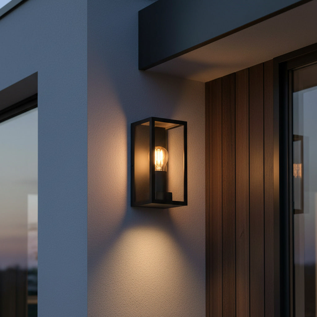 black outdoor wall sconce shown at night next to a front door on the wall 
