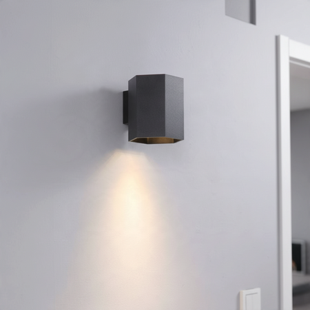 Ultra Beam Lighting Ltd hexagonal black LED wall downlight casting a warm 3000K light beam on a grey interior wall