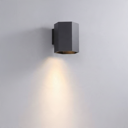 Ultra Beam Lighting Ltd black hexagonal LED wall downlight casting a warm 3000K light beam on a grey wall.