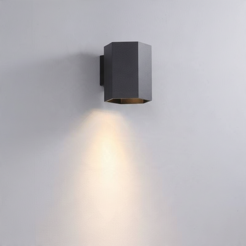 Ultra Beam Lighting Ltd black hexagonal LED wall downlight casting a warm 3000K light beam on a grey wall.