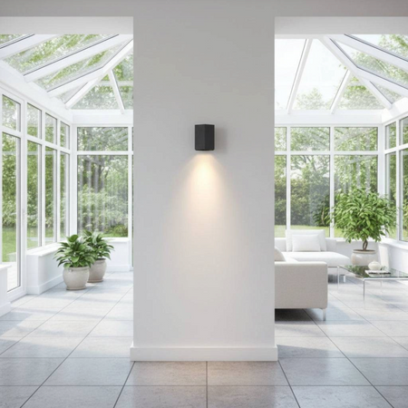 Ultra Beam Lighting Ltd black hexagonal LED wall down light casting a warm glow on a white interior wall.