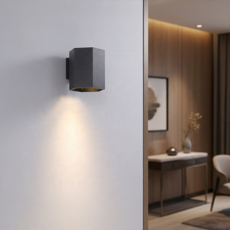 Ultra Beam Lighting Ltd black hexagonal LED wall down light casting a warm 3000K beam on a white interior wall.