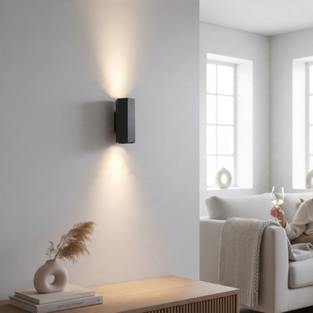 Ultra Beam Lighting Ltd black hexagonal up and down wall light casting warm light on a modern living room wall