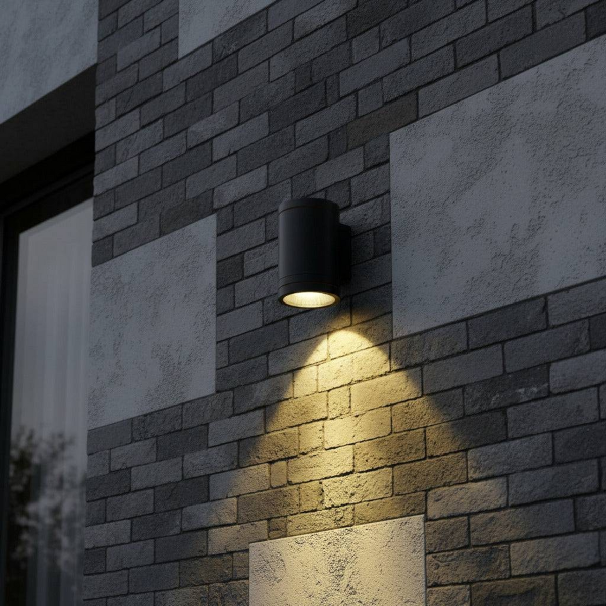 Ultra Beam Lighting Ltd 12W LED black outdoor wall downlight casting a warm focused beam on a grey brick wall.