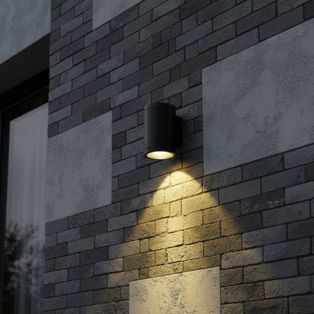 Ultra Beam Lighting Ltd 12W LED black outdoor wall downlight casting a warm focused beam on a grey brick wall.