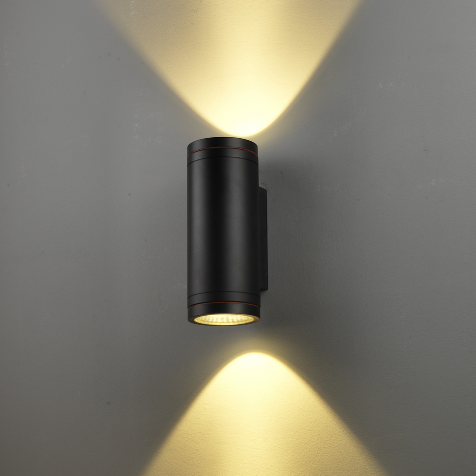 Ultra Beam Lighting Ltd 24W black LED outdoor wall light with dual-directional warm light beams on a grey wall.