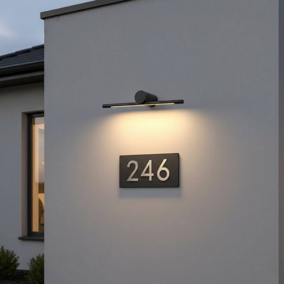 Ultra Beam Lighting Ltd 6W black LED sign wall light with rotatable head illuminating a house number on a grey wall.
