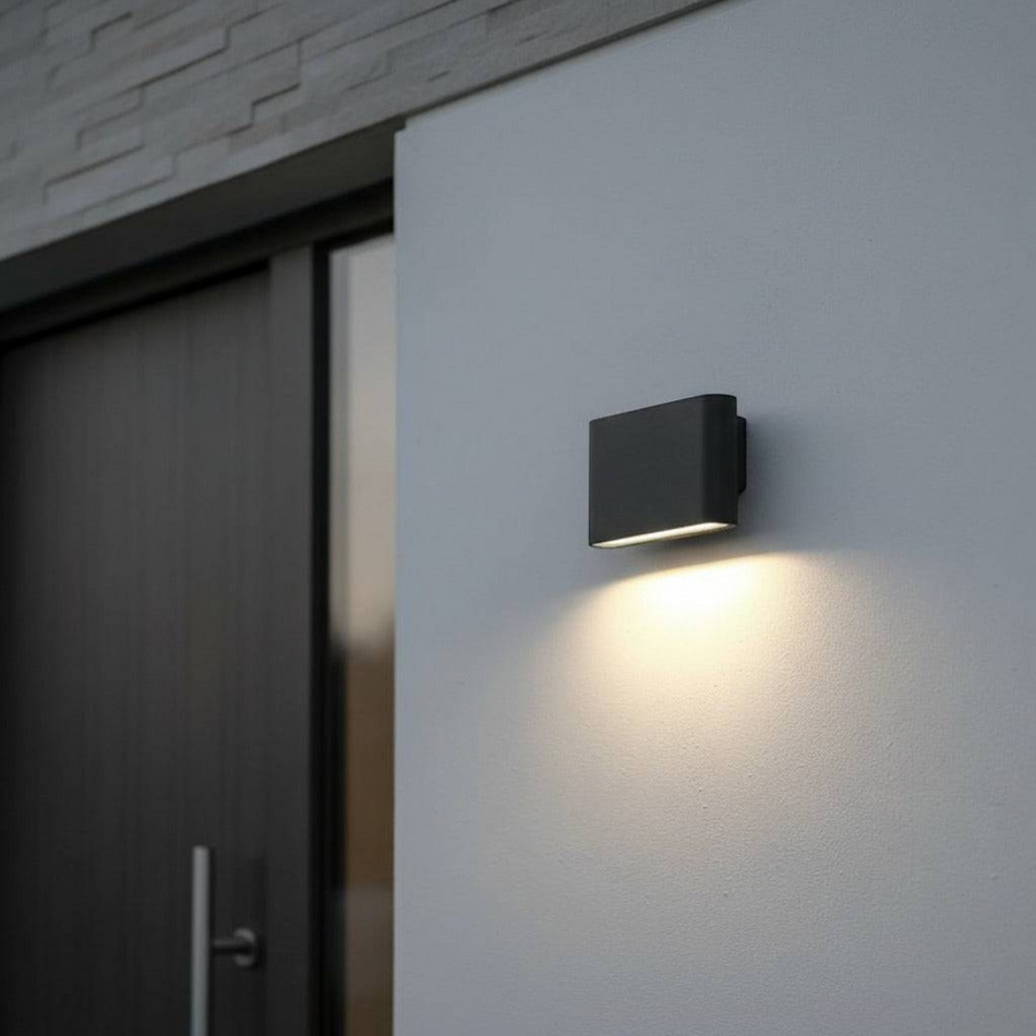 black outdoor LED wall downlight mounted on a white exterior wall next to the front door of a home