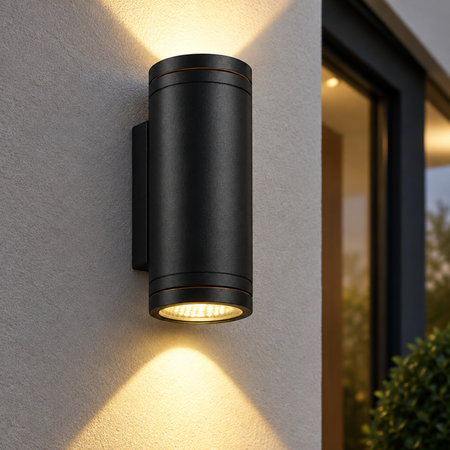 Ultra Beam Lighting Ltd 24W black cylindrical LED outdoor wall light casting dual beams on a textured exterior wall.