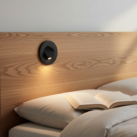 Ultra Beam Lighting Ltd black recessed LED reading light mounted on a wooden headboard above a bed with an open book.
