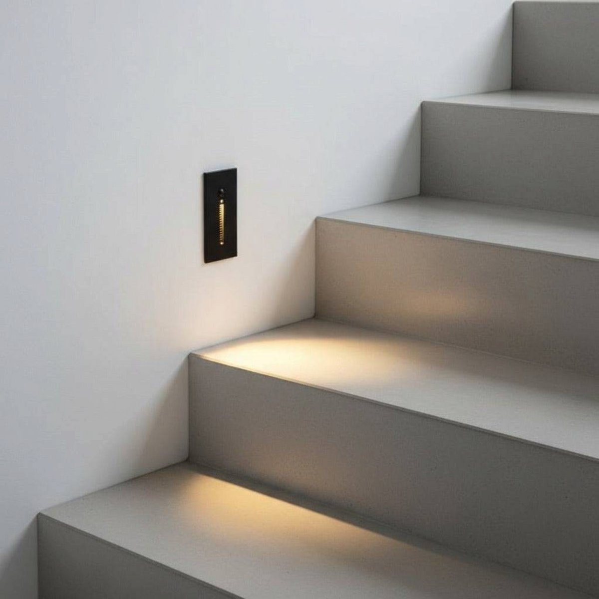 Ultra Beam Lighting Ltd black recessed motion sensor stair light casting warm white glow on concrete steps