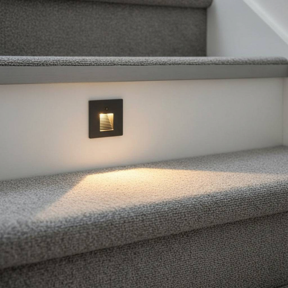 Ultra Beam Lighting Ltd black recessed motion sensor stair light casting warm illumination on a carpeted step