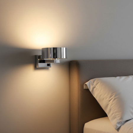 Ultra Beam Lighting Ltd modern chrome LED bedside wall reading light emitting a warm glow in a bedroom setting.