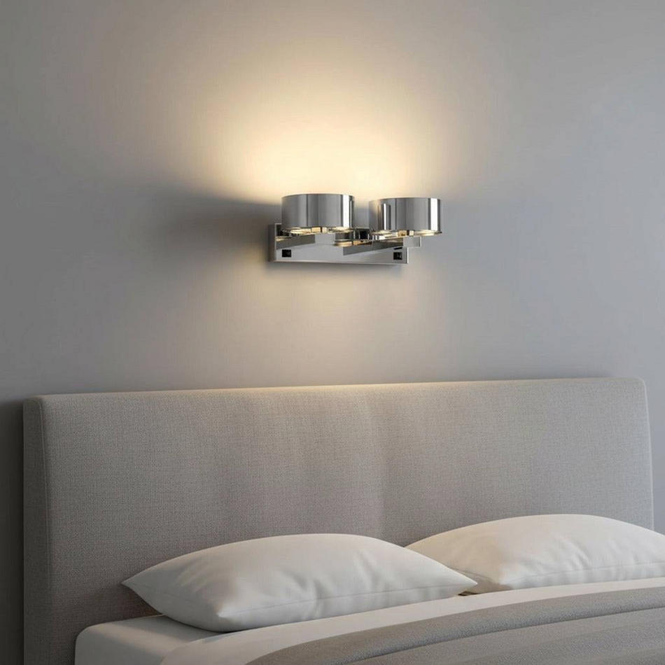 Ultra Beam Lighting Ltd dual head chrome LED wall light mounted above a grey upholstered headboard emitting warm light
