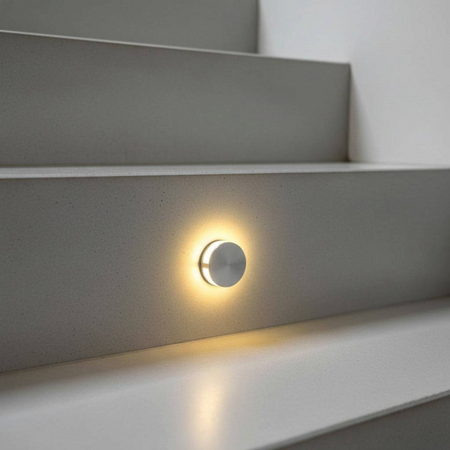 Ultra Beam Lighting Ltd Halo round 1W LED recessed step light in brushed aluminum emitting a warm glow on a staircase