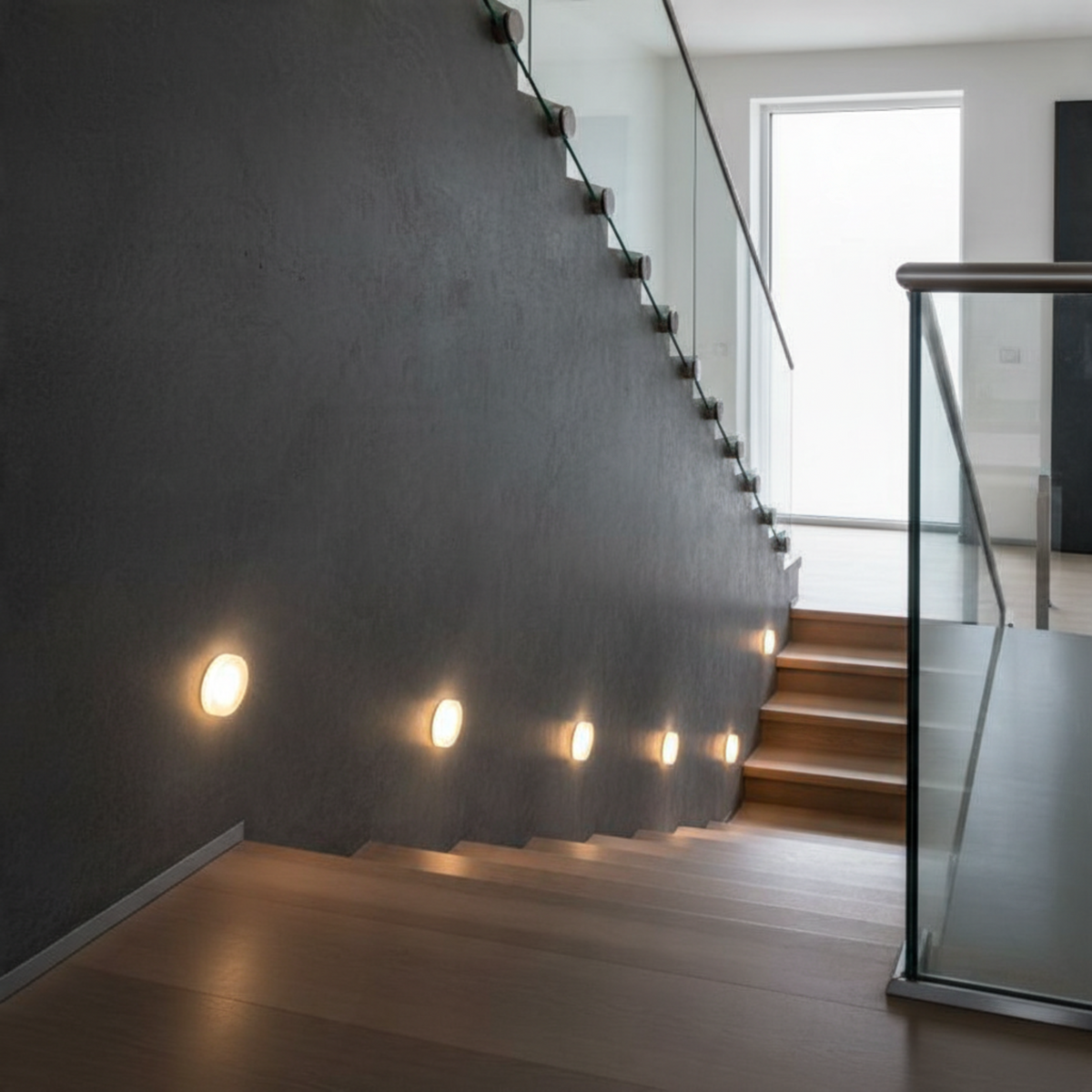 Ultra Beam Lighting Ltd round 1 watt recessed LED stair tread lights installed along a dark grey interior staircase.