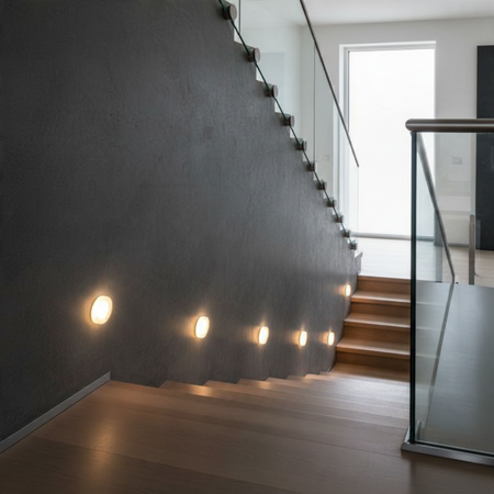 Ultra Beam Lighting Ltd round 1 watt recessed LED stair tread lights installed along a dark grey interior staircase.