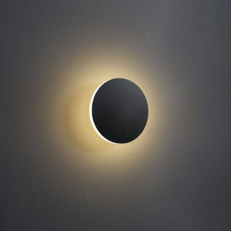 Ultra Beam Lighting Ltd round matte black LED wall sconce with a warm halo light effect on a dark wall