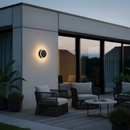 Ultra Beam Lighting Ltd round black LED outdoor wall lamp with halo glow mounted on a modern patio exterior wall.