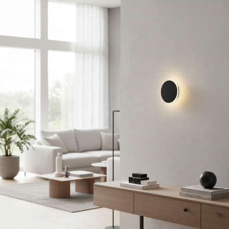 Ultra Beam Lighting Ltd round matte black LED wall sconce creating a warm halo light effect in a modern living room.
