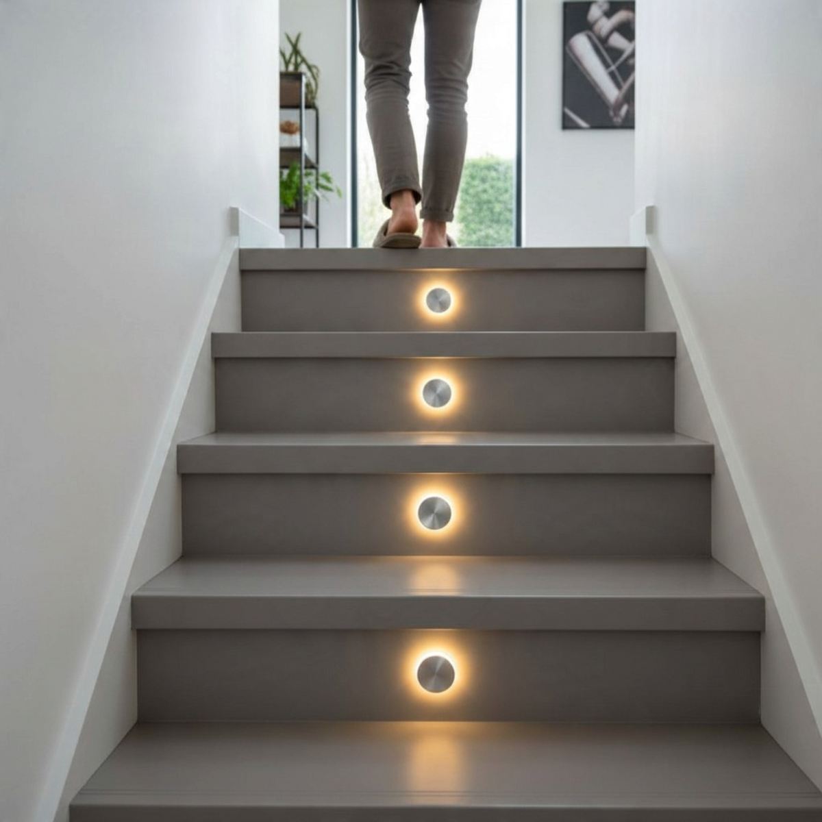 Ultra Beam Lighting Ltd round recessed LED step lights installed in grey staircase treads creating a warm halo effect