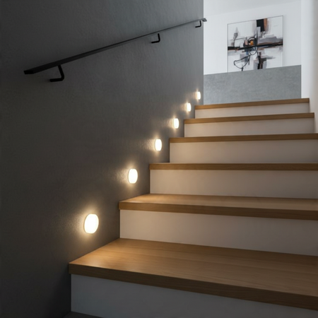 Ultra Beam Lighting Ltd round 1 watt LED recessed stair tread lights with soft acrylic diffusers on a dark wall.