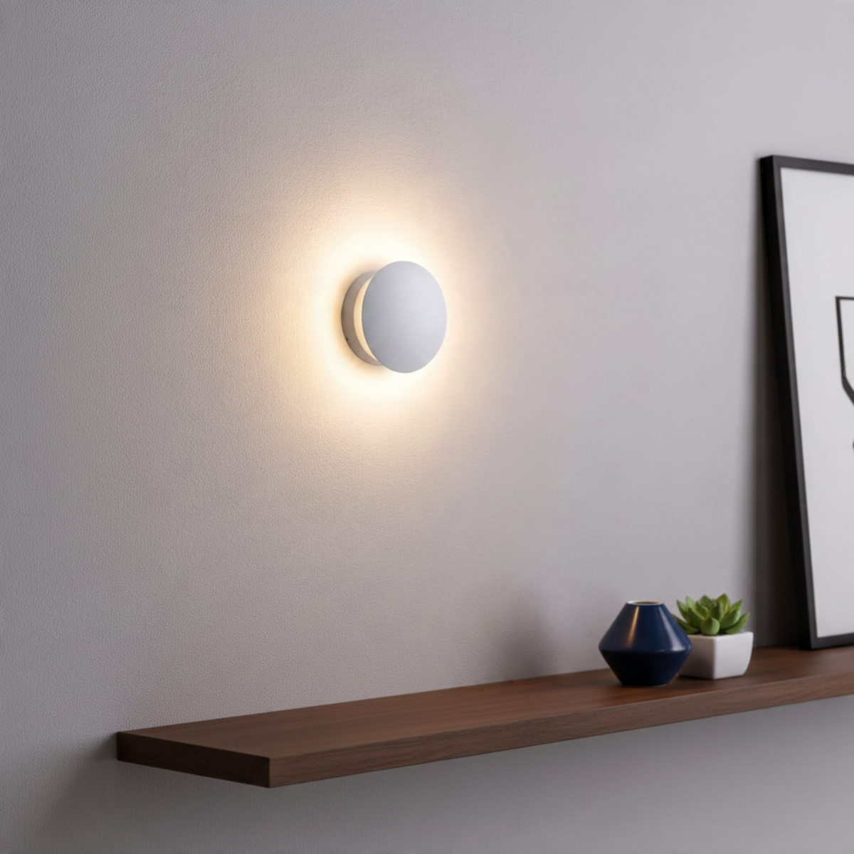 Ultra Beam Lighting Ltd round white LED wall light casting a soft halo effect on a grey interior wall above a shelf.