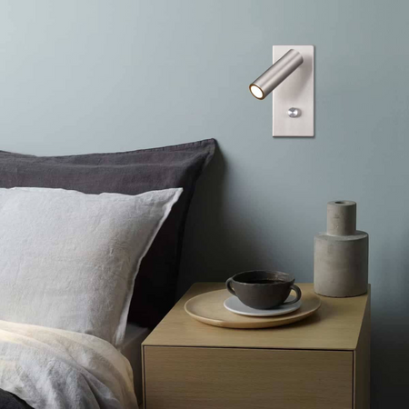 brushed nickel dimmable reading lamp mounted on the wall next to a bed with a side table