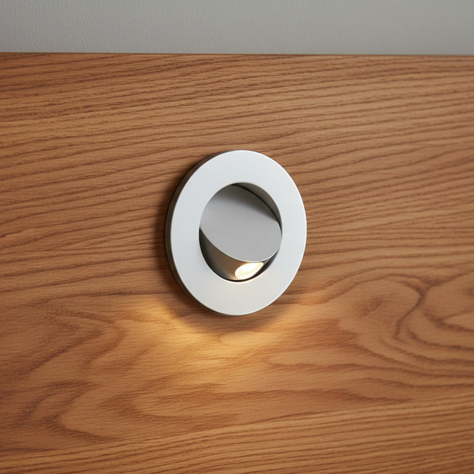 Ultra Beam Lighting Ltd silver round recessed LED reading light tilted open on a wooden headboard