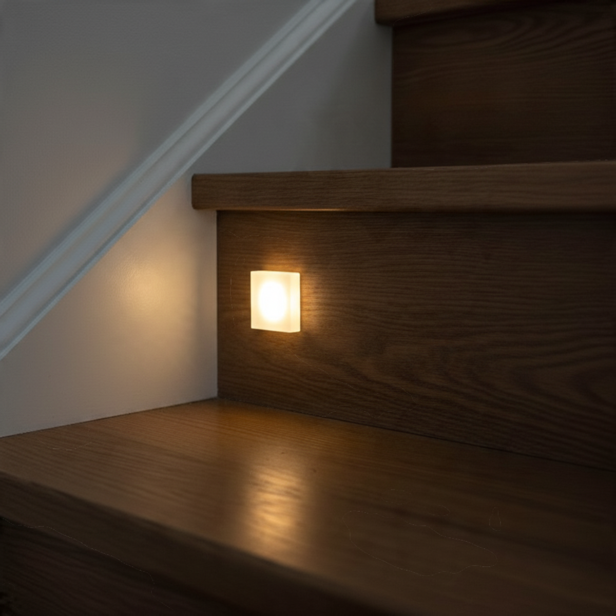Ultra Beam Lighting Ltd square recessed LED stair light with sandblasted acrylic face glowing on a wooden staircase