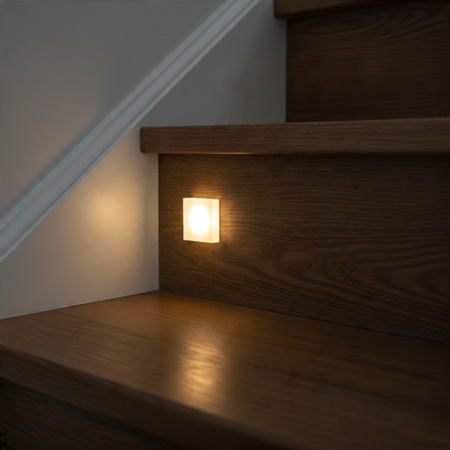 Ultra Beam Lighting Ltd square recessed LED stair light with sandblasted acrylic face glowing on a wooden staircase
