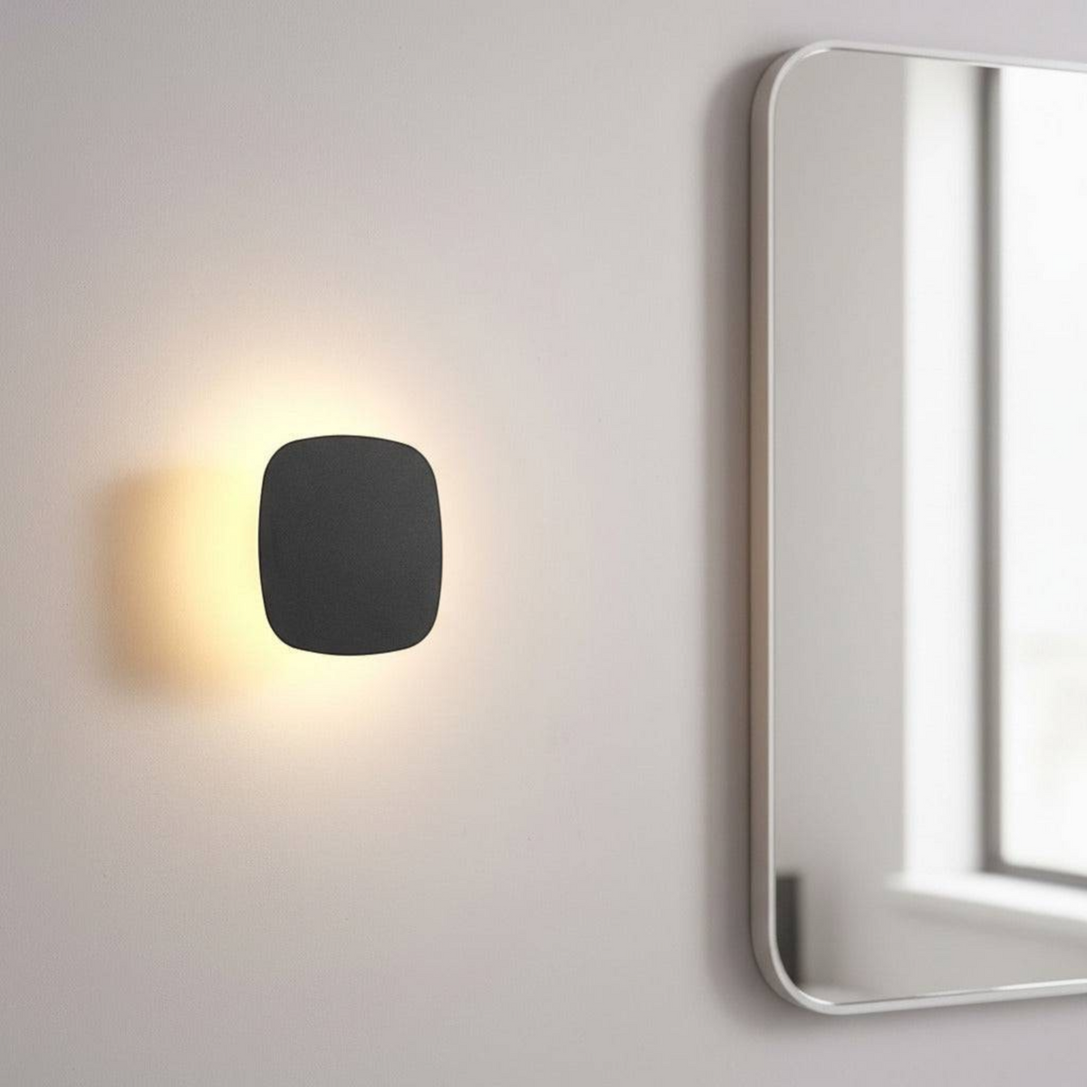 Ultra Beam Lighting Ltd square black LED vanity wall light with warm halo glow mounted next to a bathroom mirror