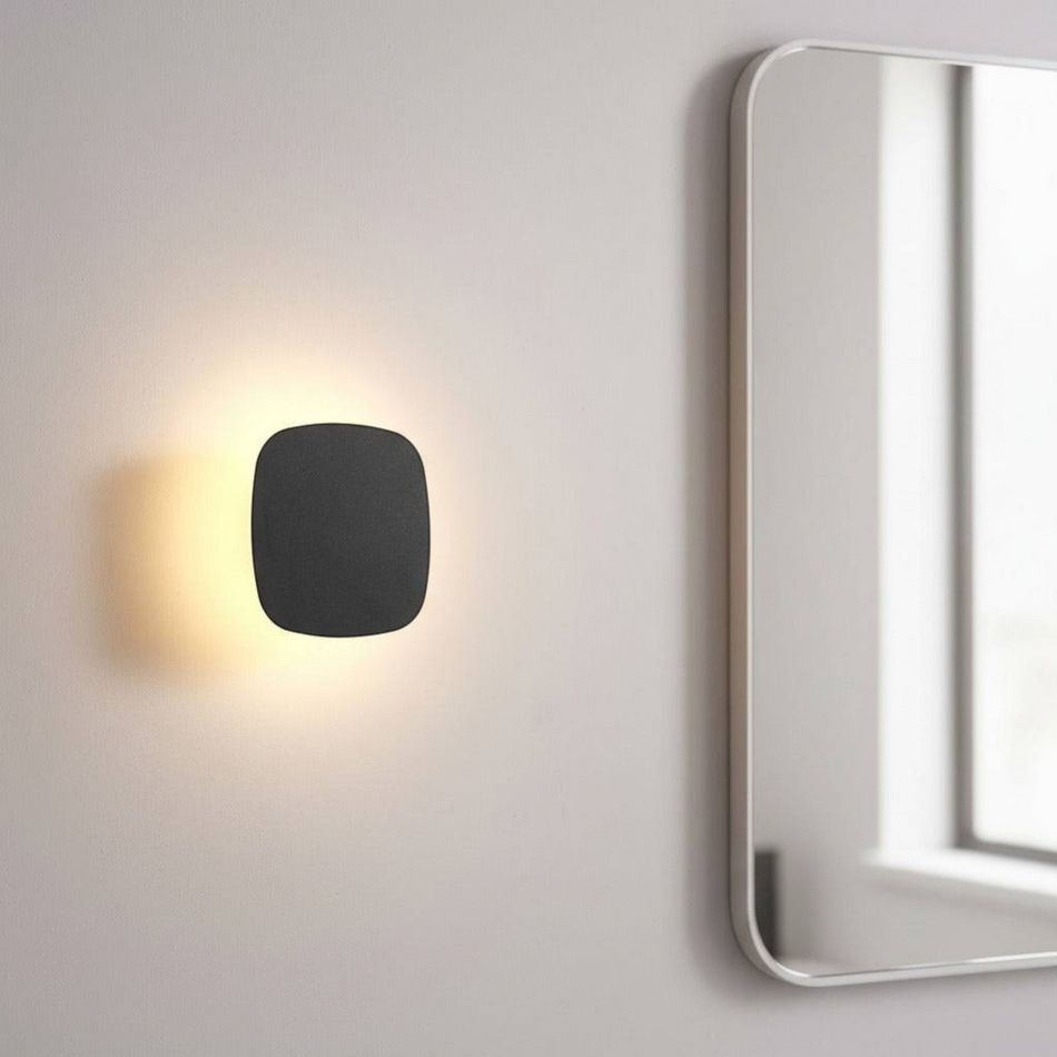 Ultra Beam Lighting Ltd square black LED vanity wall light with warm halo glow mounted next to a bathroom mirror