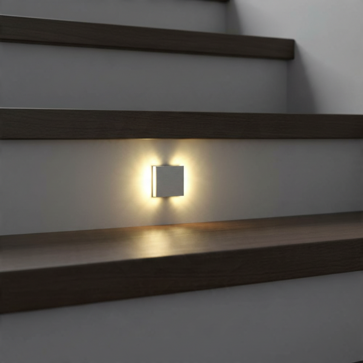 Ultra Beam Lighting Ltd Halo square 1 watt brushed aluminum recessed LED stair light glowing on a dark wall