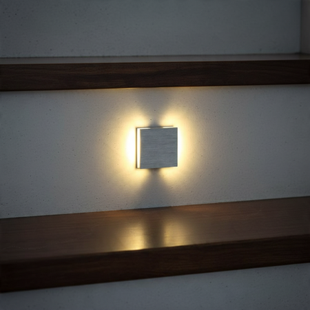 Ultra Beam Lighting Ltd square brushed aluminum LED stair light recessed in a wall with warm light wash
