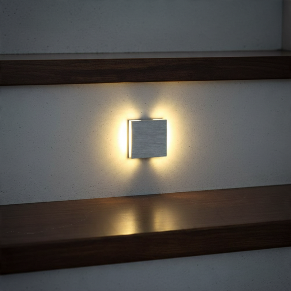 Ultra Beam Lighting Ltd square brushed aluminum LED stair light recessed in a wall with warm light wash